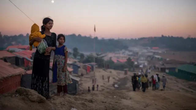 A Rohingya family look out over the camps at sunset