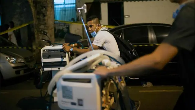 Profissionais de saúde carregam equipamentos para fora do hospital