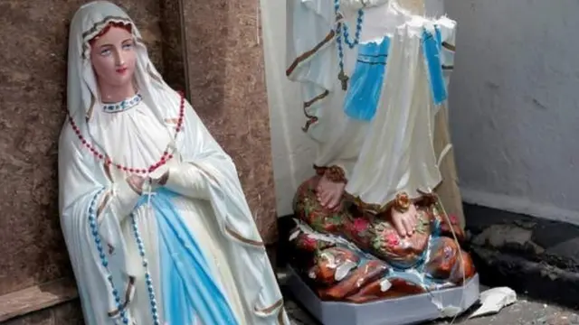 খ্রিস্টানরা যাকে মাদার মেরি বলে মানেন, মেরির মূর্তি গির্জার সামনে এভাবে ভেঙে পড়ে আছে