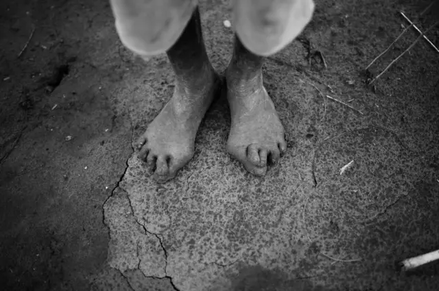 An elderly man's feet on the hard earth