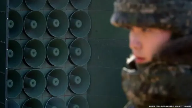 ਲਾਊਡ ਸਪੀਕਰਾਂ ਸਾਹਮਣੇ ਖੜ੍ਹਾ ਇੱਕ ਫੌਜੀ