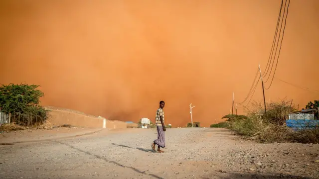 Un homme marche devant une tempête de sable à Dollow, dans le sud-ouest de la Somalie. Des personnes de tout le Gedo en Somalie ont été déplacées à cause de la sécheresse. 14 avril 2022