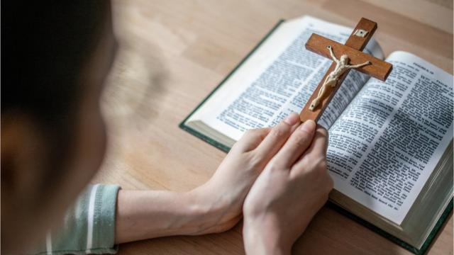 Mulher reza com crucifixocard guard pokermãos sobre a Bíblia