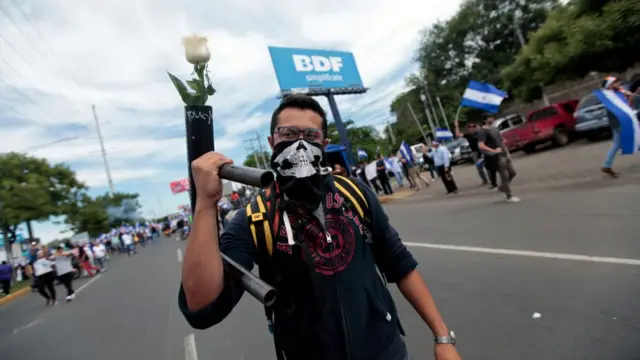 Manifestante con mortero del que sale una rosa blanca.