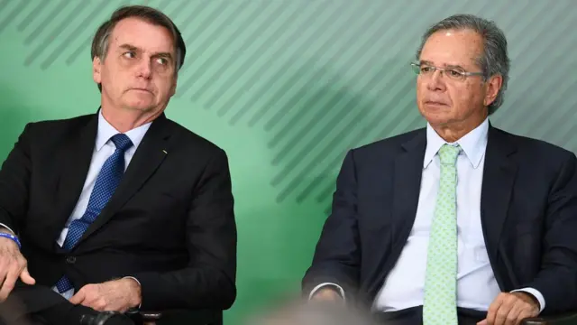 Jair Bolsonaro e seu ministro da Economia, Paulo Guedes, aparecem sentados durante evento