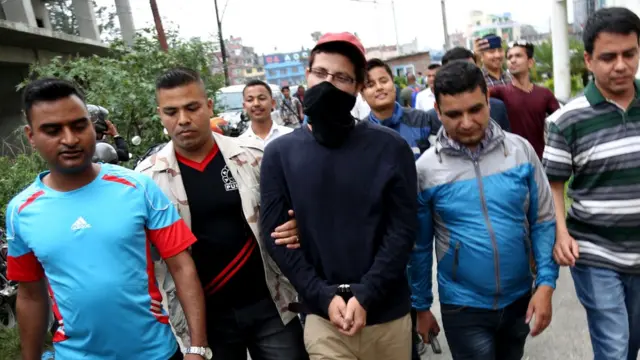 चूडामणि उप्रेतीलाई पक्राउ गृह मन्त्रालयमा आयोजित पत्रकार सम्मेलनमा लगिँदै।