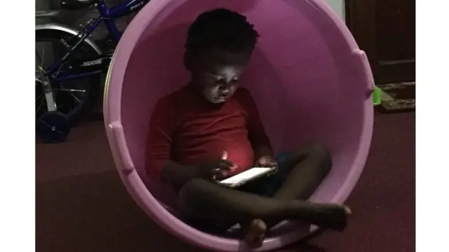 Umwana ari mw'ibase akina kuri telefone