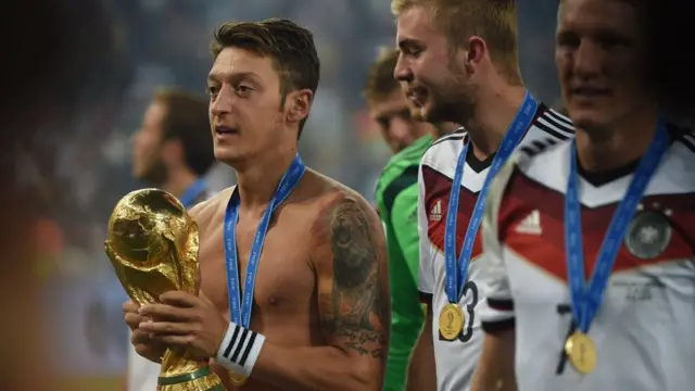 In this file photo taken on July 13, 2014, Germany"s midfielder Mesut Ozil celebrates holding the World Cup trophy