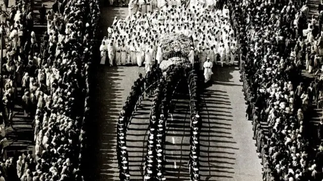 ဂန္ဒီဈာပနအခမ်းအနားမှာ သူ့ရုပ်အလောင်းဘေးက ရေတပ်အစောင့်တပ်ဖွဲ့က ချန်ရံလိုက်ပါ ပို့ဆောင်