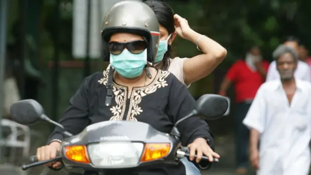 ఇన్ఫెక్షన్ సోకకుండా ముఖానికి మాస్క్ కట్టుకుని బైక్ నడుపుతున్న మహిళ