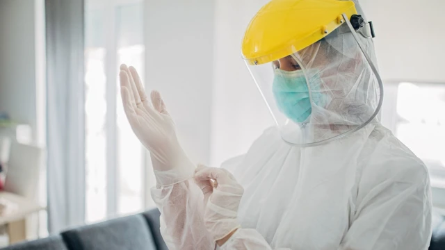 મહિલા આરોગ્યકર્મી ગ્લવ્ઝ પહેરતાં