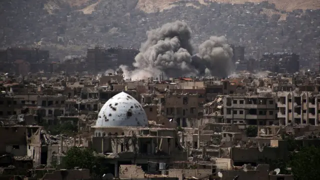 Humo saliendo de un edificio en un distrito controlado por rebeldes en Damasco, luego de un ataque aéreo.