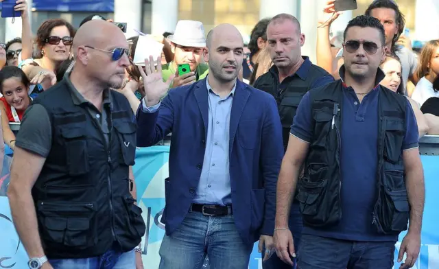 Roberto Saviano (centro) junto a tres guardaespaldas.