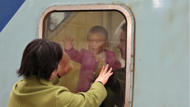 A Chinese baby waves to her mother