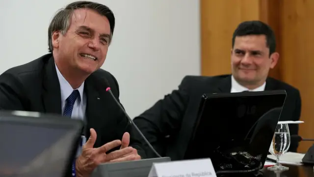 Bolsonaro fala ao microfone ao ladoapostar nos jogos do brasileiraoMoro; ambos sorriem, sentados