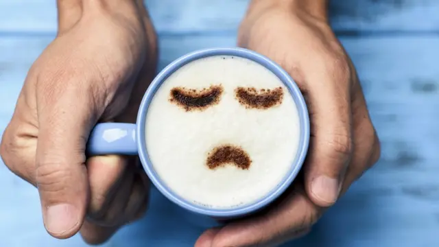 Una taza de café con un cara triste