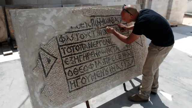 Un arqueólogo limpia un mosaico en griego de hace 1.500 años.