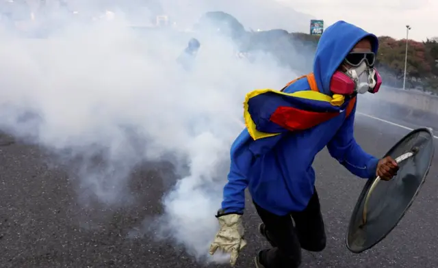Activista venezolano devuelve un gas lacrimógeno.
