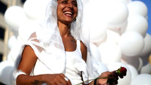 An activist from the Lebanese NGO Abaad (Dimensions), a resource centre for gender equality, dressed as a bride and wearing bandages, smiles while holding a rose as she celebrates in Beirut on August 17, 2017,