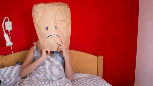 Mujer con una bolsa de papel en la cabeza.