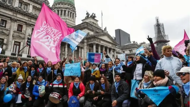 Opponents of the bill wave flags outside Congress