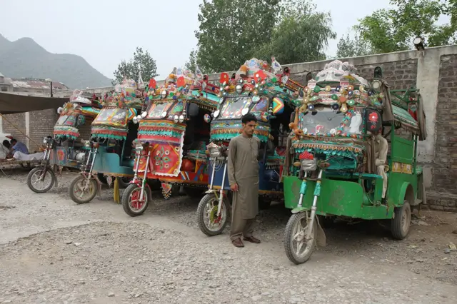 Dekorisane autorikše čekaju putnike u Mardanu, Pakistan. Iako se za dekorisana vozila uglavnom koristi termin ’Truck Art’, kamioni nisu jedini predmet ukrašavanja: autorikše, autobusi, minibusi i rikše takođe se ukrašavaju na sličan način.