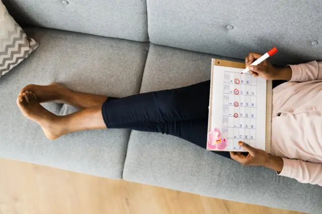 Mulher deitada no sofá com calendário