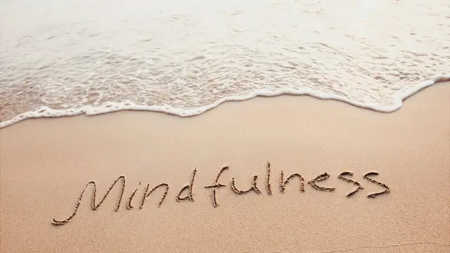 Playa con la palabra "mindfulness" escrita en la arena