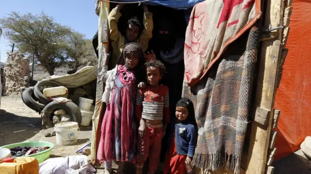 أطفال يقفون أمام خيمة تؤويهم في اليمن