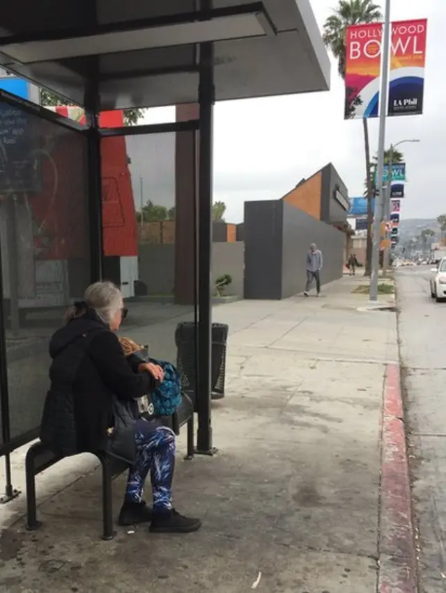 Una mujer sin casa en una parada de autobús en Los Ángeles