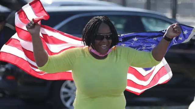 Una mujer con una bandera de EE.UU. celebra el triunfo de Biden en Wilmington, Delaware.