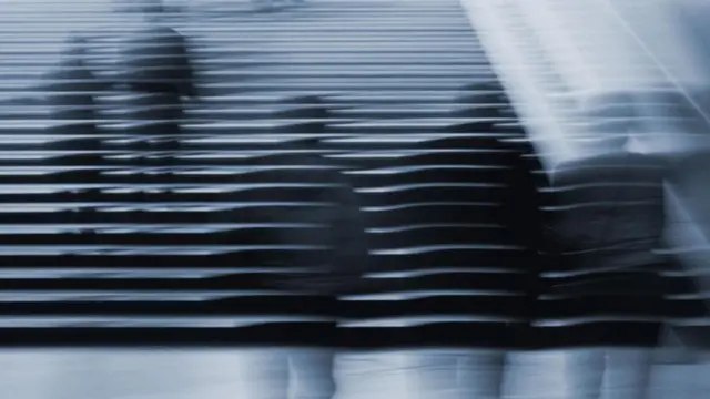 Imágenes desdibujadas de personas que suben por unas escaleras.