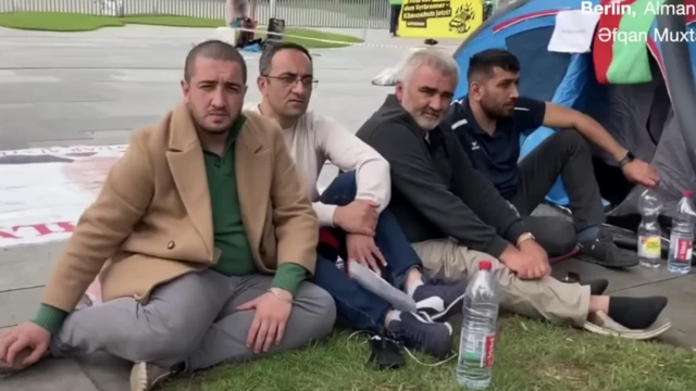 Группа мужчин сидит у палатки на улице города