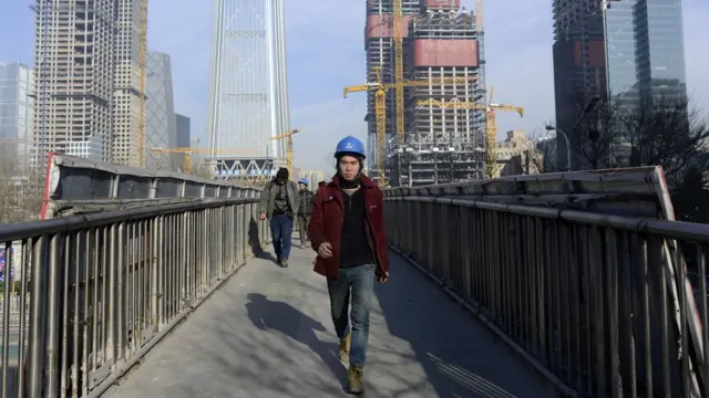 Pekerja Cina berjalan di jembatan di Beijing, 16 Desember 2016.