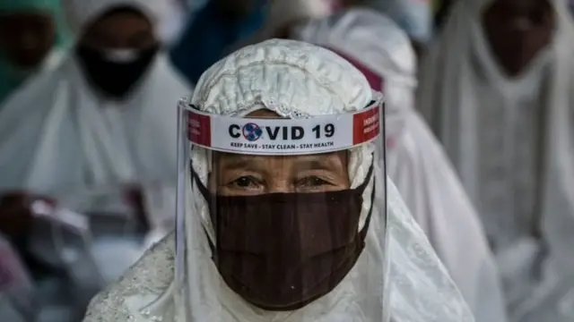 Seorang perempuan usia lanjut mengenakan masker dan pelindung wajah.