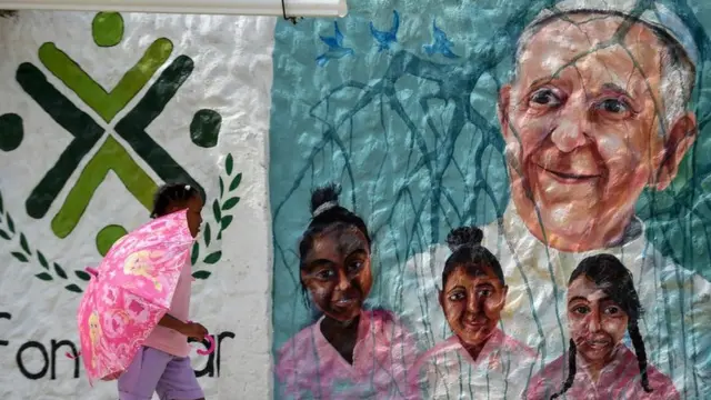Niña pasa frente a un mural con la cara del papa Francisco en Cartagena de Indias, Colombia.