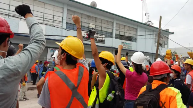 Equipo de rescatistas y voluntarios al lado del edificio derrumbado.