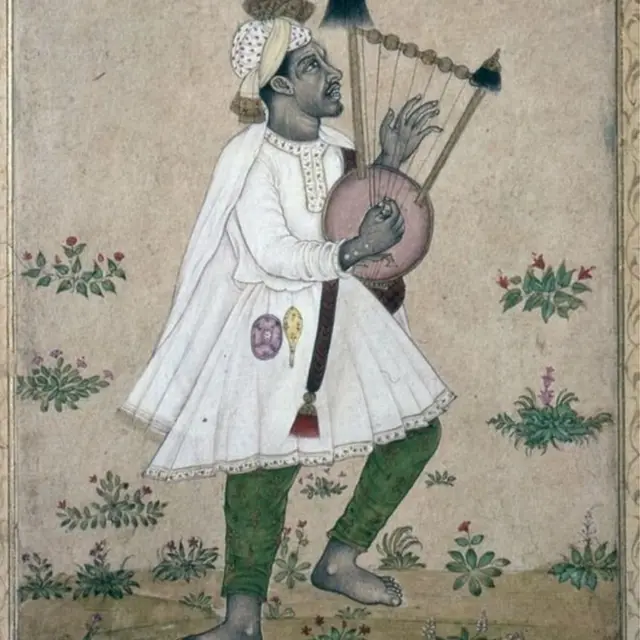 వీణ లాంటి పరికరాన్ని వాయిస్తున్న ఆఫ్రికన్.