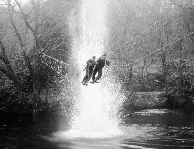 Comandos británicos traviesan un río bajo fuego simulado de artillería durante un ejercicio de entrenamiento, en Escocia.