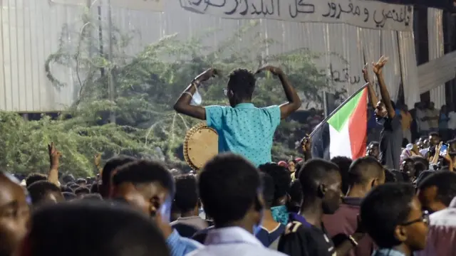 Two people sitting one others' shoulders at a sit-in at the military HQ in Khartoum, Sudan - Sunday 7 April 2019