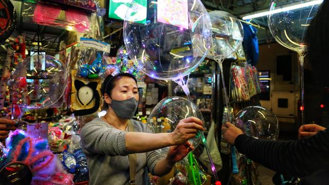 小賣店老闆娘熱情招待購買發光氣球的顧客。