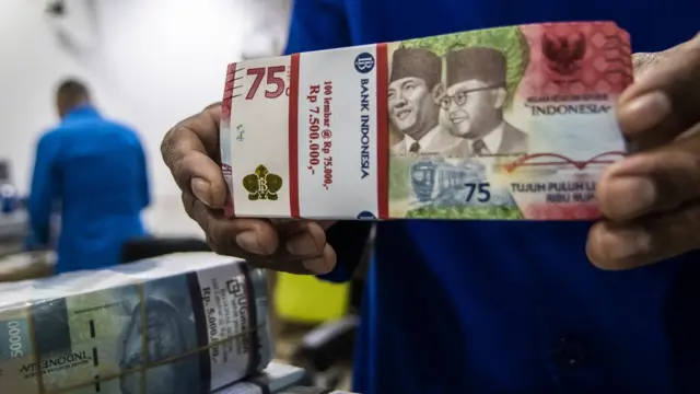 Petugas menyusun tumpukan uang di Cash Pooling Bank Mandiri, Jakarta, Kamis (23/06). Dewan Gubernur Bank Indonesia pada Juni 2022 memutuskan untuk mempertahankan suku bunga acuan sebesar 3,5 persen.