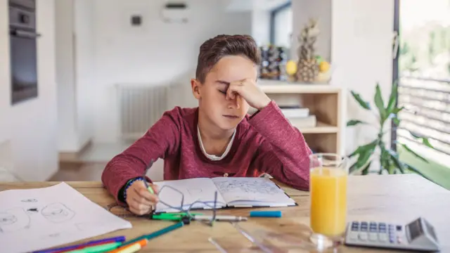 Un niño que se toma la cara mientras estudia
