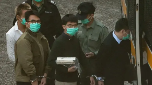 Pro-democracy activists Joshua Wong (C) and Ivan Lam (L) board a Hong Kong Correctional Service van ahead of a sentence hearing