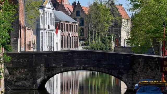 Foto de uma paisagem belga: rio, ponte e casas ao fundo