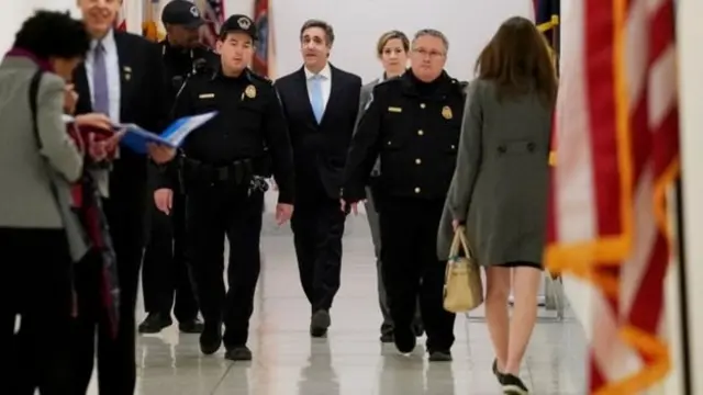 Майкл Коен іде коридором з поліцейськими