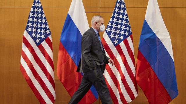 A member of a delegation walks past US and Russian flags displayed at the US permanent Mission, in Geneva during Russia-US talks