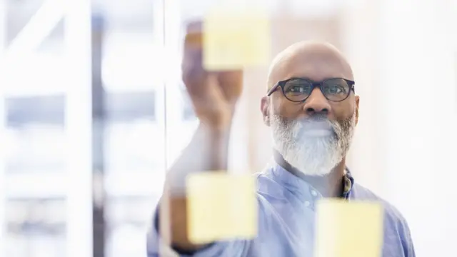 Hombre pegando papeles en un vidrio