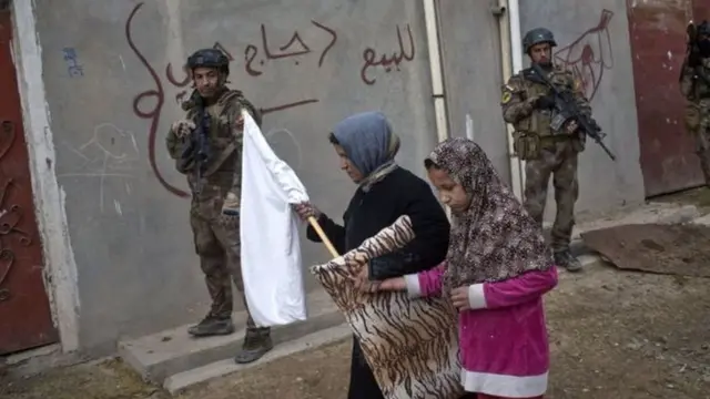 इराकी सेना के सड़कों में आइएस लड़ाकों को खोज़ने के दौरान नागरिक सफ़ेद झंडा लिए हुए