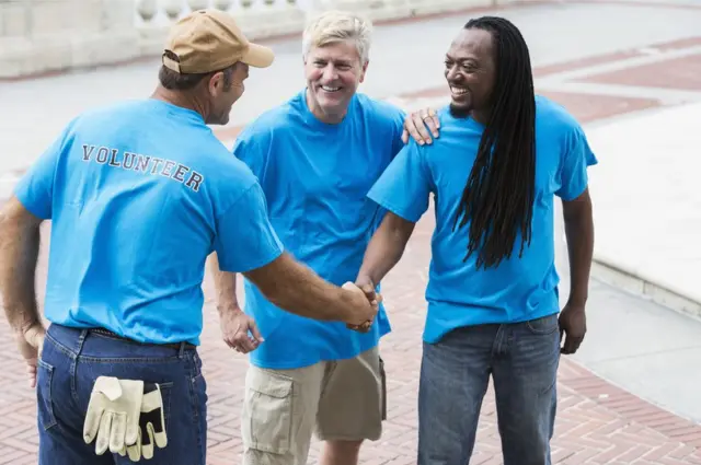 Tres voluntarios se saludan.